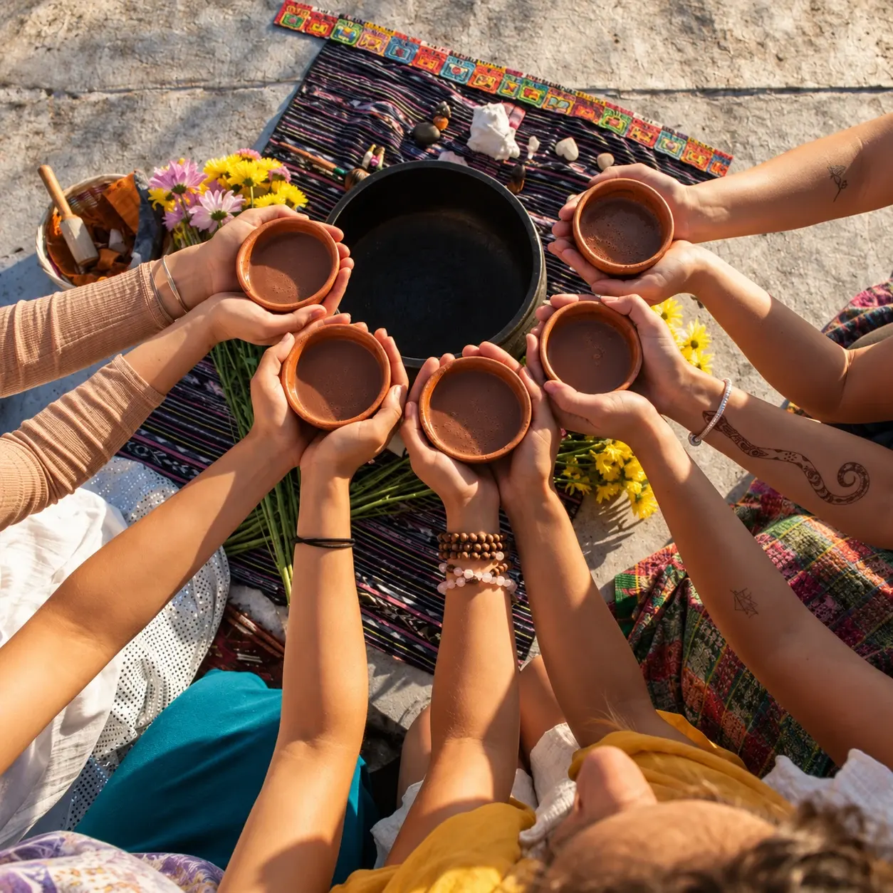 Participants holding cups together at a cacao ceremony