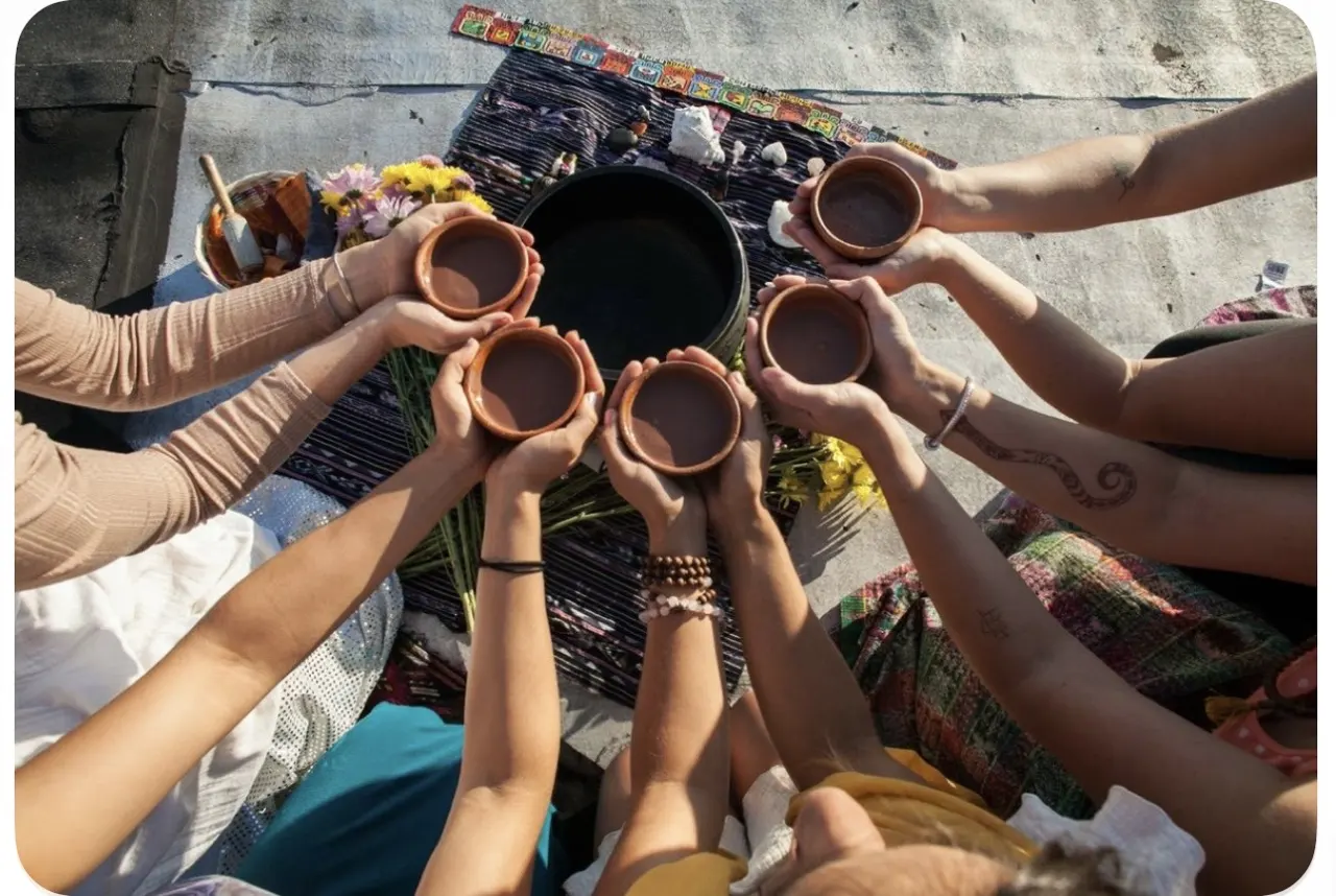 A circle of participants holding cups of cacao together