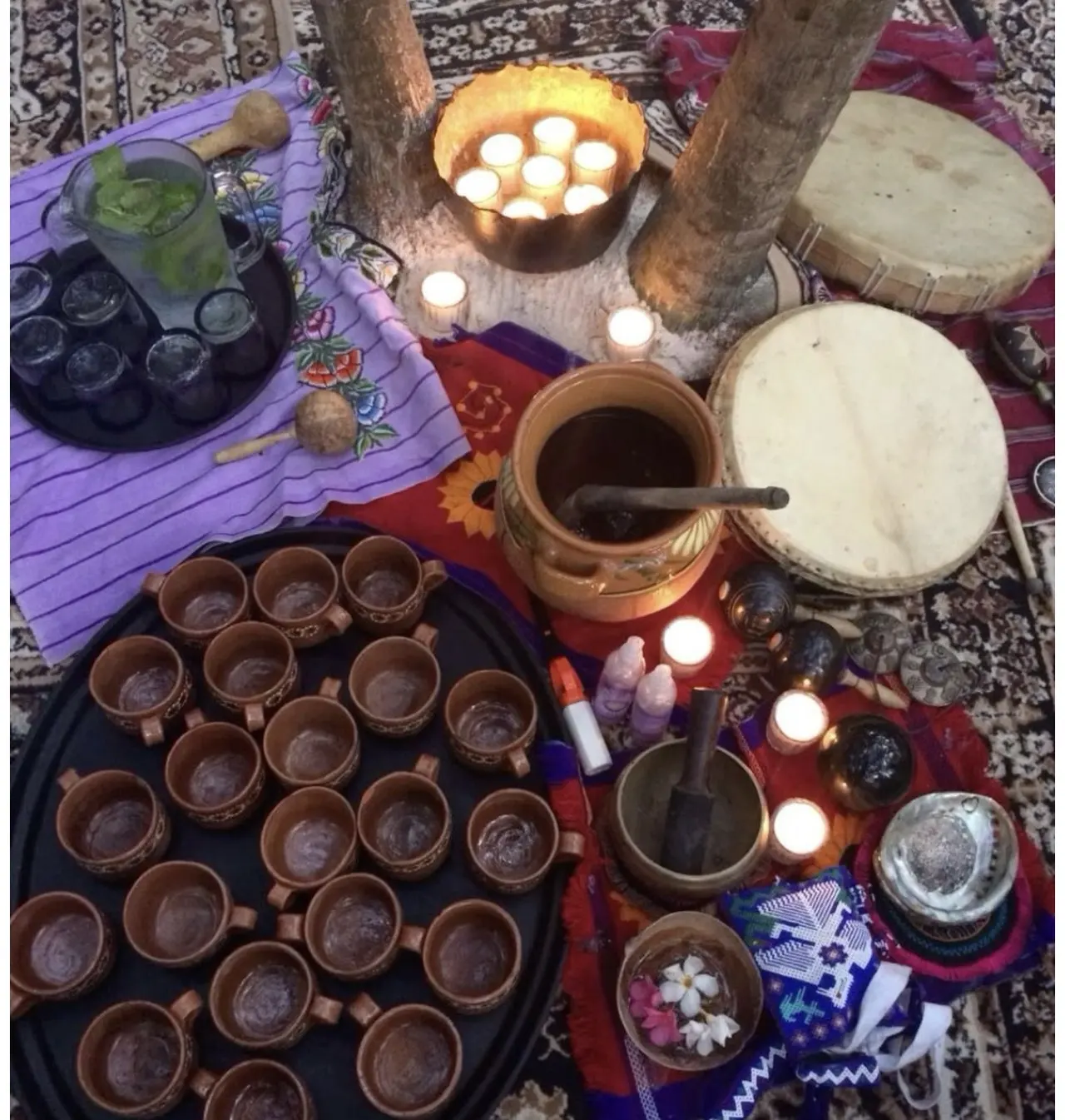 Ceremonial cacao cups arranged beside candles and drums