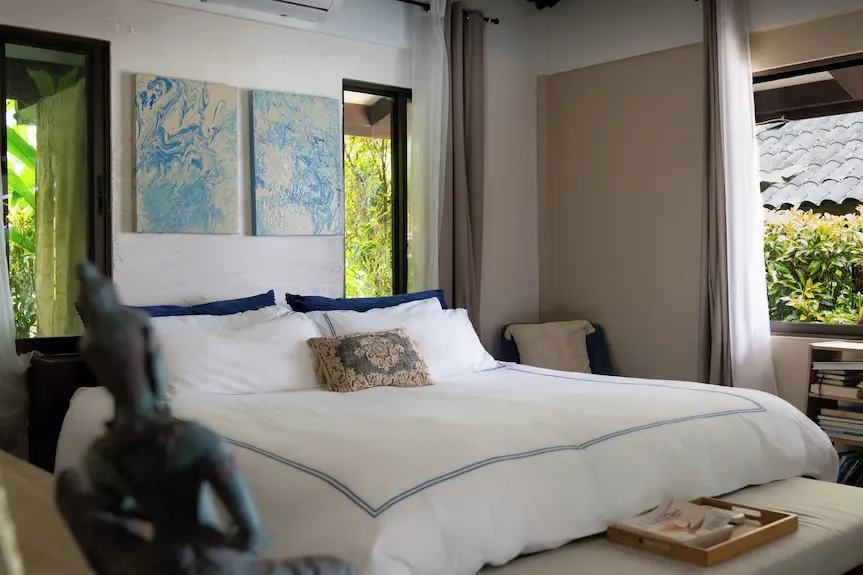 White bedding and blue artwork in a restful tropical room